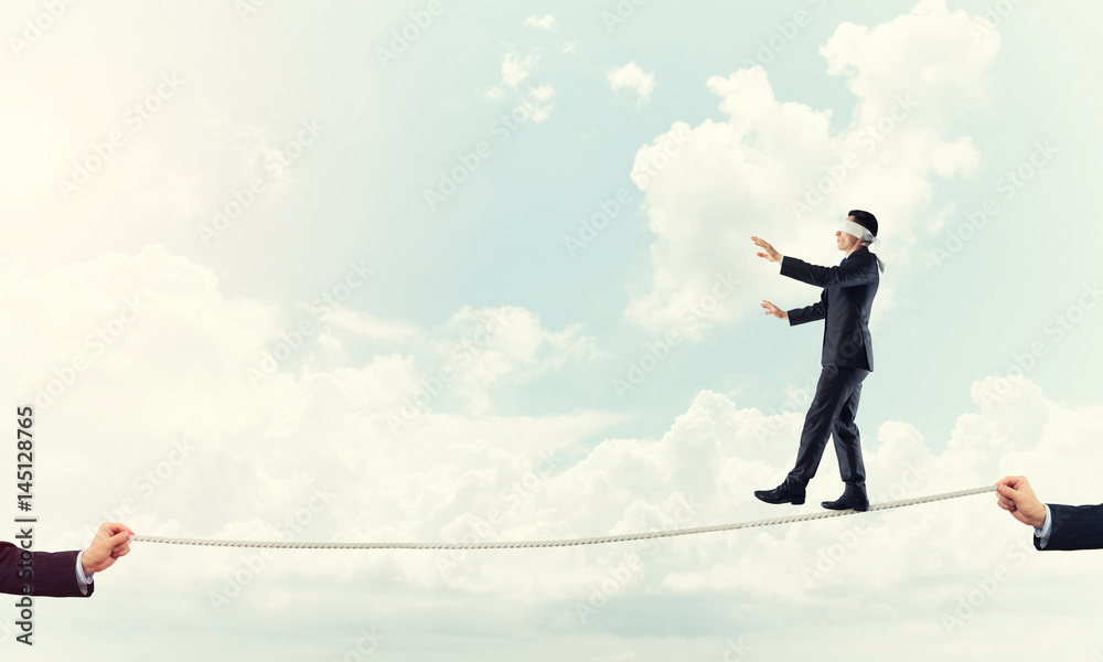 Business concept of risk support and assistance with man balancing on rope Business concept of risk support and assistance with man balancing on rope