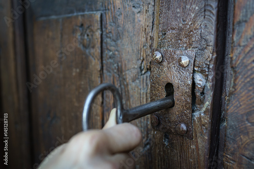 Selective focus vintage keyhole with key on a antique wooden door