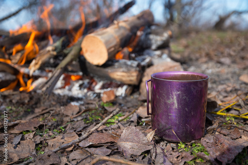 Cup with coffee is standing next to a campfire