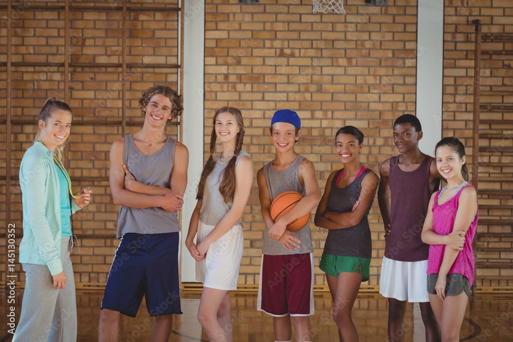 Fototapeta premium Female coach and high school kids standing in basketball court