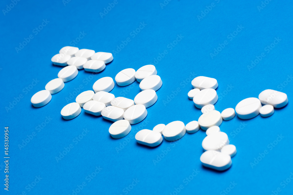 Word TAX made of white pills on blue background Word TAX made of white pills on blue background