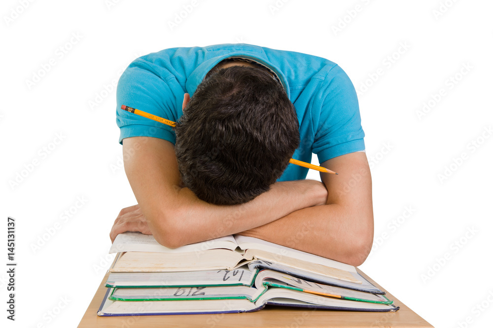 Teenage boy resting his head with a pencil thru it on a pile of books isolated on white Teenage boy resting his head with a pencil thru it on a pile of books isolated on white