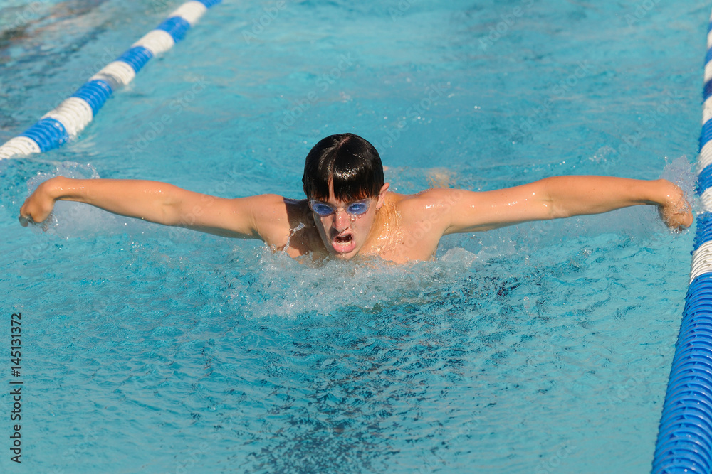 Male competitive swimmer swimming the butterfly stroke in a meet