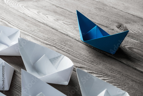 Business leadership concept with white and color paper boats on 