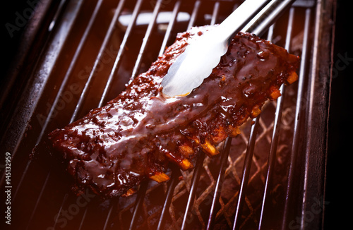 Obraz na płótnie Close up of Smoked Barbecue Pork Spare Ribs on hot flaming grill, selective focus w salonie