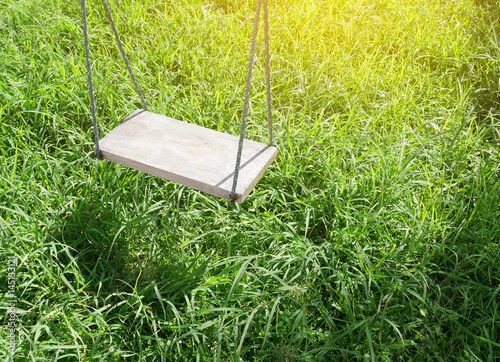 Obraz na płótnie Wooden swing with green grass background in the park w salonie