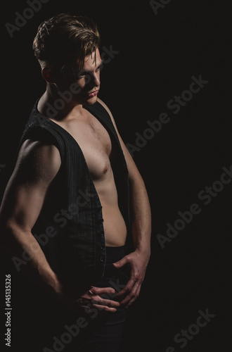 Handsome man posing in unbutton vest with muscular torso