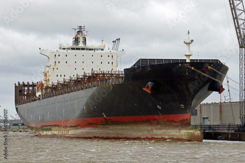 schwarzes Containerschiff liegt unbeladen in Bremerhaven