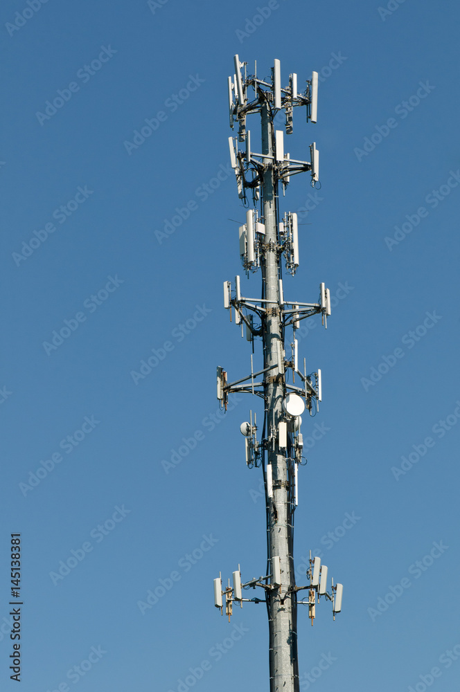 Cell phone communications tower isolated against a deep blue sky Cell phone communications tower isolated against a deep blue sky