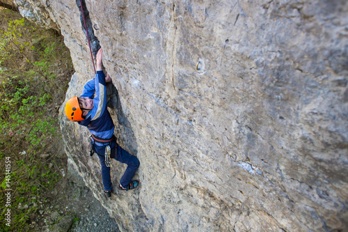 Kid rock climber climbs the cliff.