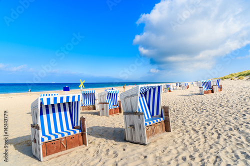 Wicker chairs on sandy beach in Kampen village on coast of North Sea, Sylt island, Germany
