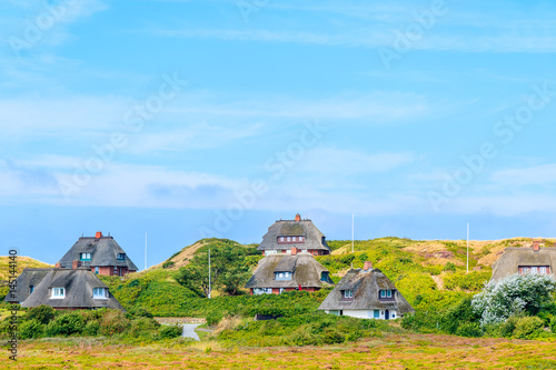 Typical Frisian houses with straw roofs on sand dunes in Kampen village, Sylt island, Germany photo