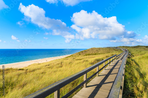 Wooden walkway along a coast of North Sea and view of beautiful beach near Wenningstedt village, Sylt island, Germany