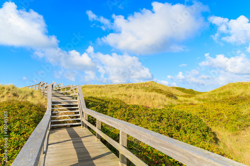 Wooden walkway along a coast of North Sea and view of beautiful beach near Wenningstedt village, Sylt island, Germany