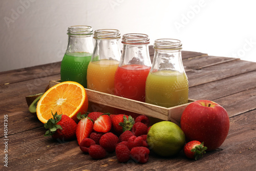 several bottles with fruit and berry juices smoothies and milkshakes , vintage wooden background, selective focus