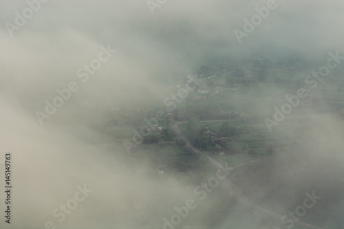 Rustic village in the mountains through the fog. The mist is high in the .mountains. Photo from top to bottom.