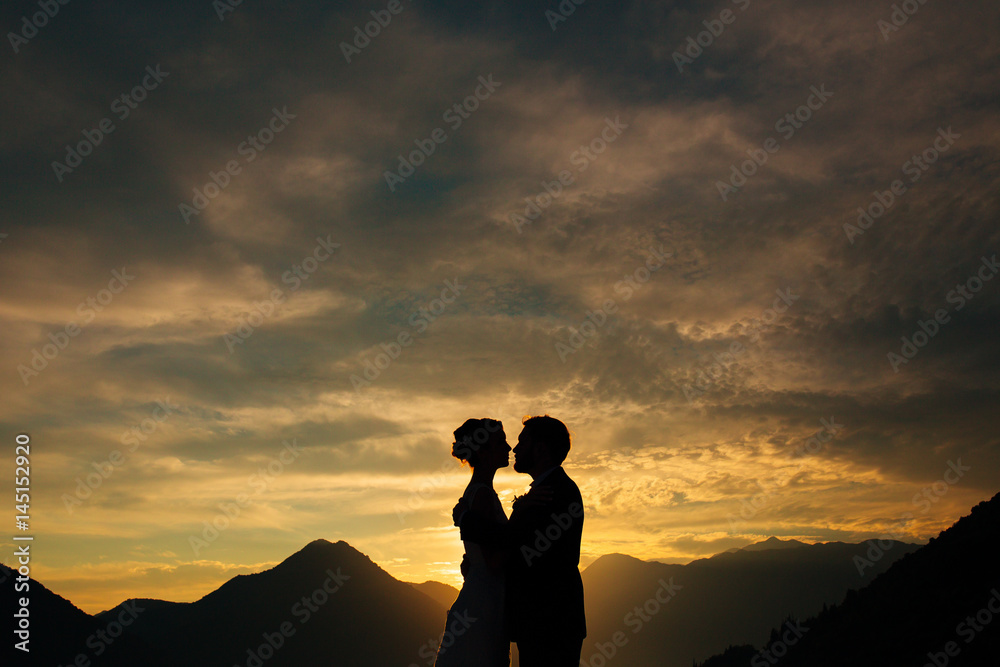 Silhouette of a newlywed couple on the background of the setting sun on the sea in Montenegro.
