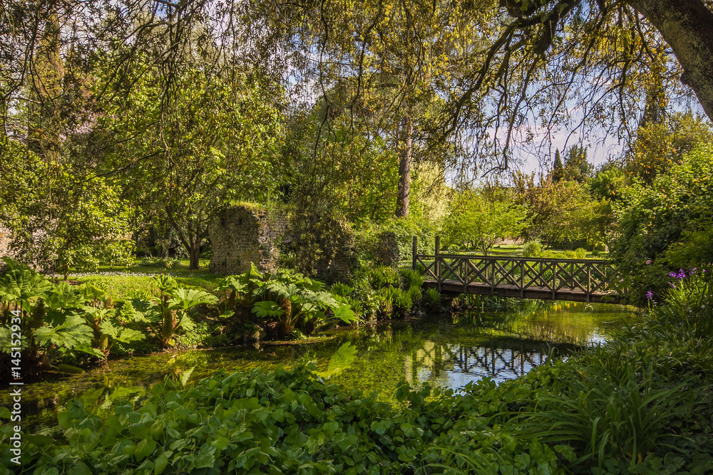 Giardino di Ninfa: piccolo ponte sopra al fiume immerso nella fitta e verde vegetazione