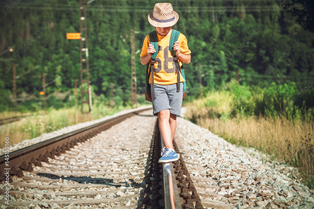 Little boy with backpack walks on railway track Little boy with backpack walks on railway track