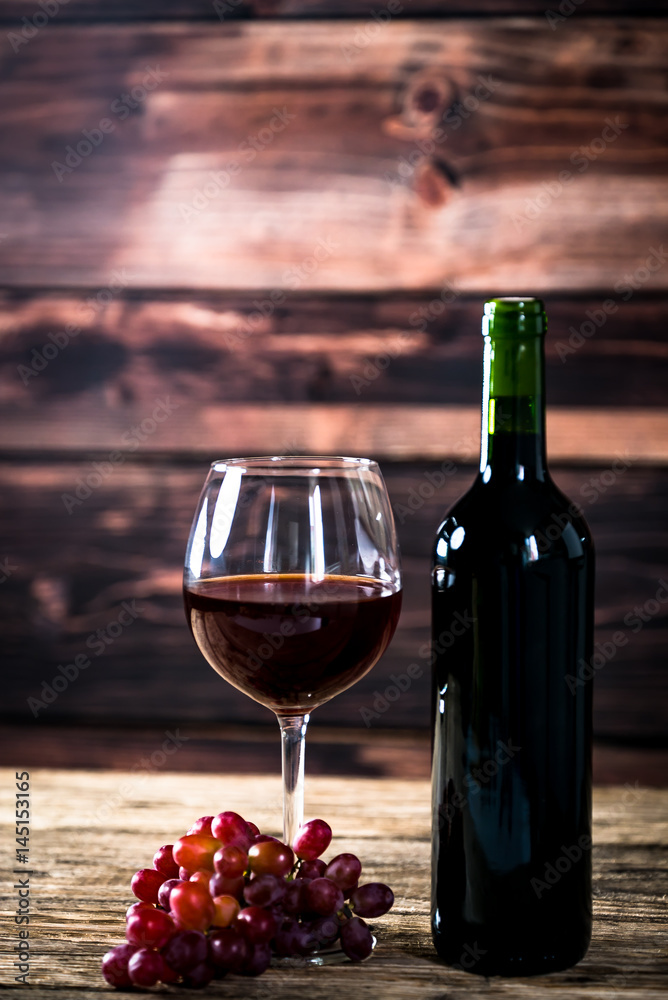 Glass bottle of wine with corks on wooden rustic table, place for typography