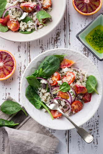 Healthy spring salad with quinoa, fresh spinach and blood oranges on white rustic background