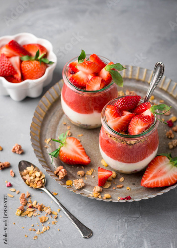 Delicious homemade granola, yogurt and strawberry parfait in glass jars 