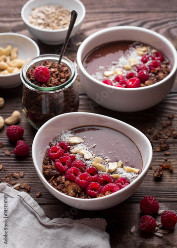 Chocolate breakfast bowls with frozen banana, cocoa, granola, raspberries, cashew nuts and coconut