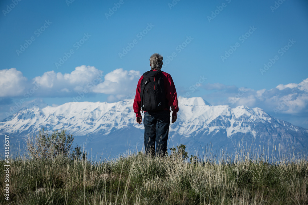 Fototapeta premium Man hiking with backpack facing mountain range