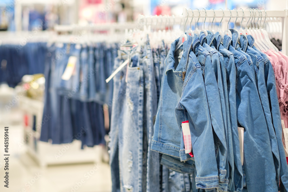 Variety of jeans jackets and jeans for girls on hangers in kids clothes store