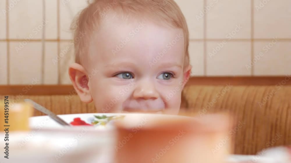 Baby 2 years old eats porridge with a spoon. Mom sits next to the boy. home furnishings Baby 2 years old eats porridge with a spoon. Mom sits next to the boy. home furnishings