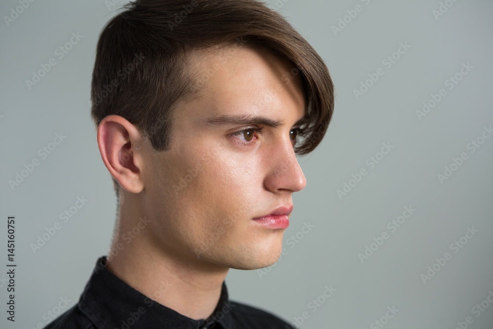 Androgynous man looking sideways against grey background Androgynous man looking sideways against grey background