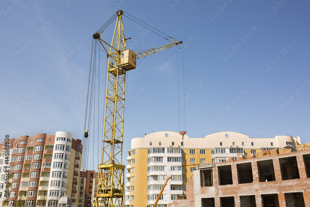 Tower crane on construction site on the background of new residential buildings Tower crane on construction site on the background of new residential buildings