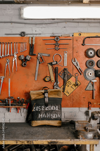Exclusive leather backpack. Backpack near the wall. The tools in the garage. Many different tools on the wall