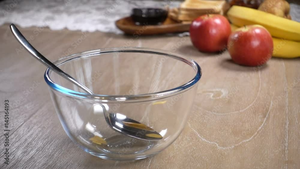 Corn flakes are poured into a glass bowl