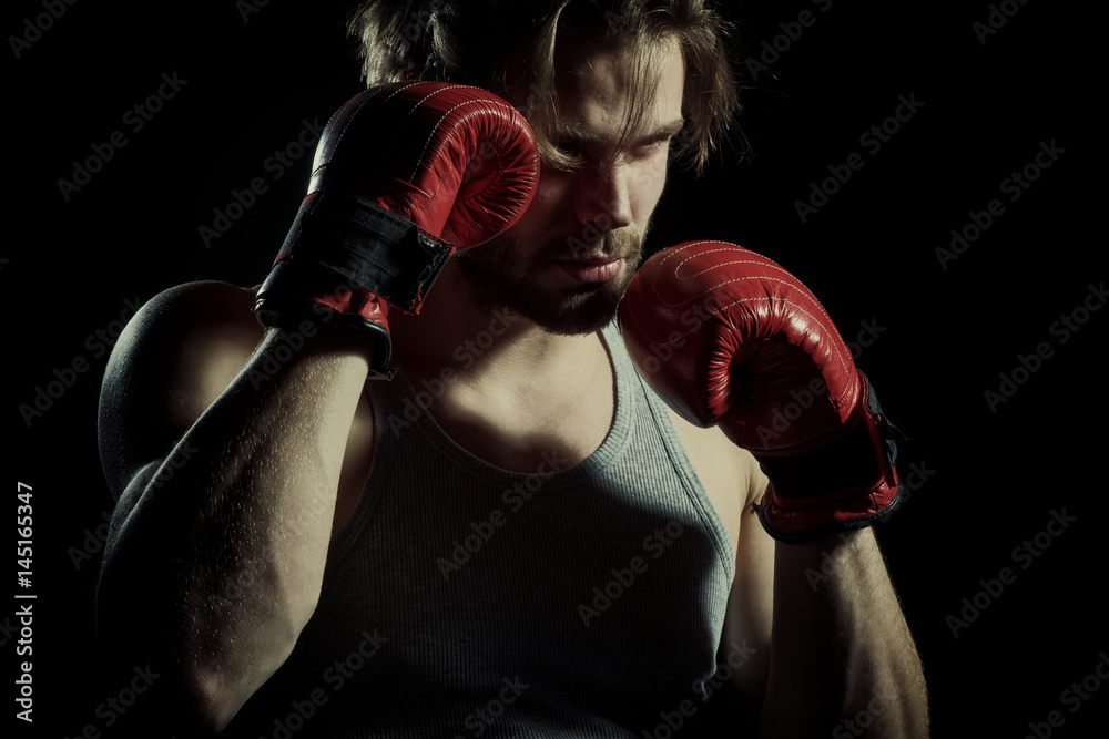 Serious men in boxing gloves are practicing. Cool young man with boxing gloves. Attractive guy boxer closeup on black background