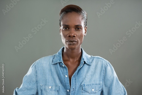 Androgynous person in denim shirt posing against grey background photo