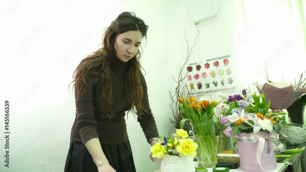 Florist making a bouquet with yellow flowers in the white gesso pot in the flower shop Florist making a bouquet with yellow flowers in the white gesso pot in the flower shop