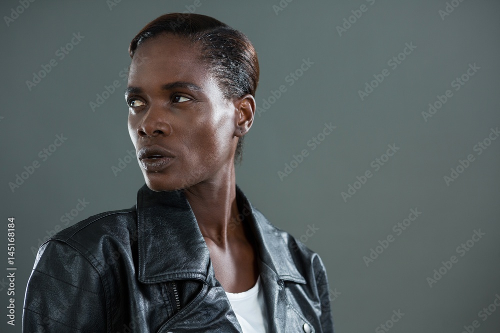 Obraz premium Androgynous man in black jacket posing against grey background