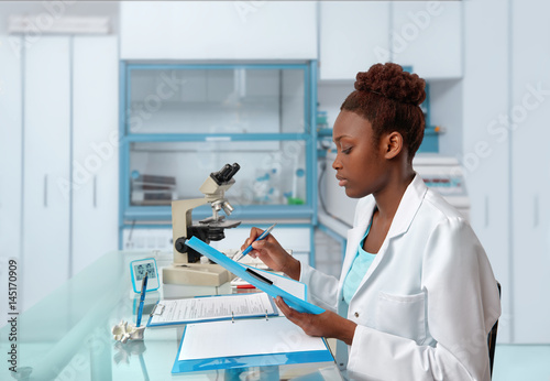African-american biologist checks records in scientific lab or research facility