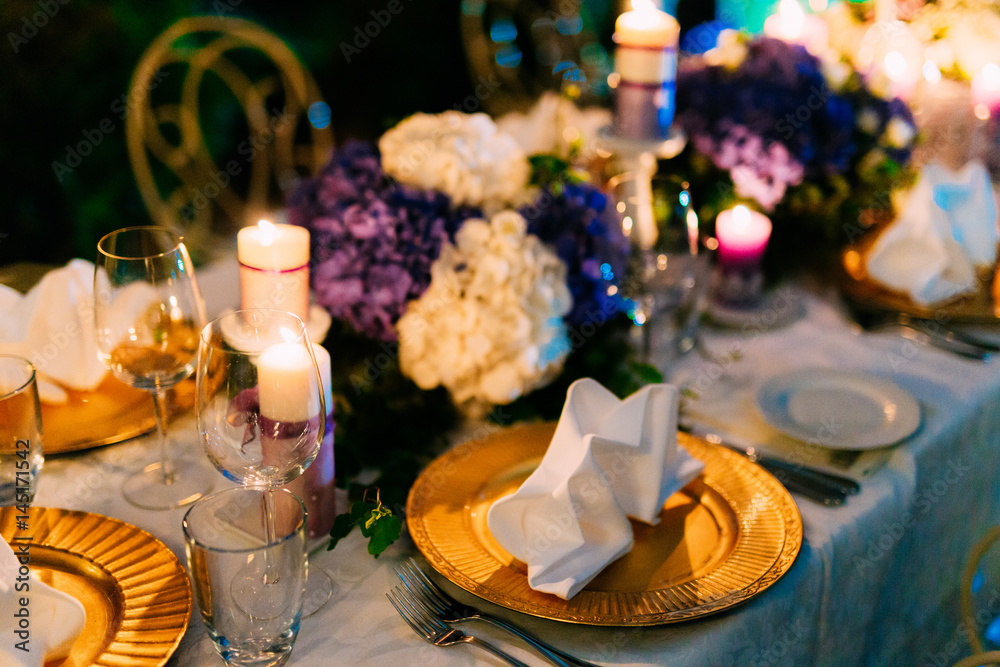 Table setting at a wedding banquet. Decoration flowers. A close-up of a plate with cutlery.