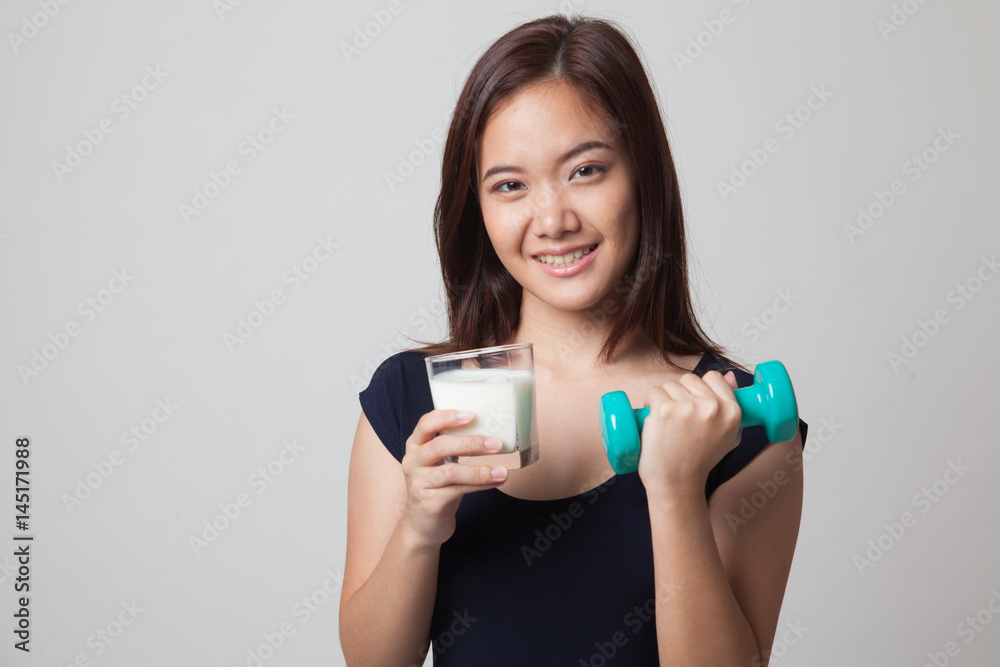 Healthy Asian woman drinking a glass of milk and dumbbell. Healthy Asian woman drinking a glass of milk and dumbbell.