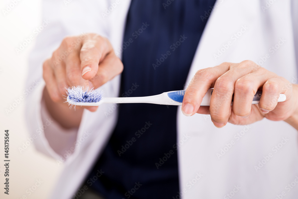 Dentist pointing at old worn out toothbrush bristle