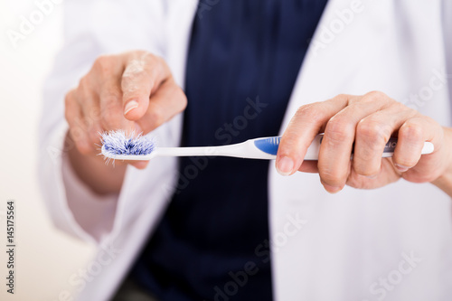 Dentist pointing at old worn out toothbrush bristle