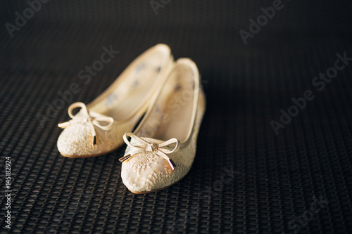 Cream shoes of the bride on the green on a black background. Weddings in Montenegro.