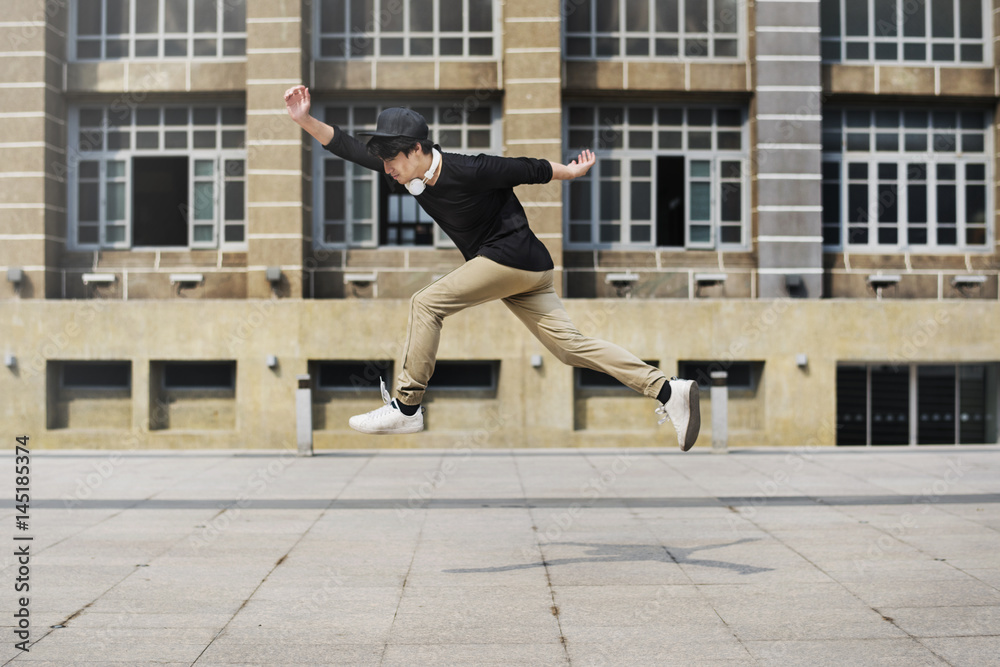 Young man jumping in frount of university campus building