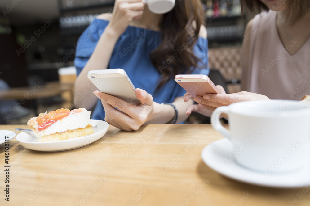 Two women are watching a smartphone at a cafe Two women are watching a smartphone at a cafe