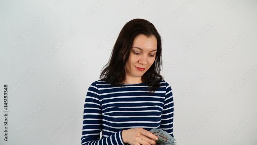 A girl with dark hair, 30-35 years old, is throwing money. Hundred-dollar curtains scatter and fall down. Shooting on white background. A girl with dark hair, 30-35 years old, is throwing money. Hundred-dollar curtains scatter and fall down. Shooting on white background.