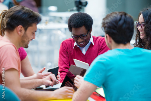Multiracial group of young students studying together. High angle shot of young people sitting at the table.