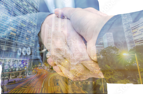 Closeup of two businessmen shaking hands against city background