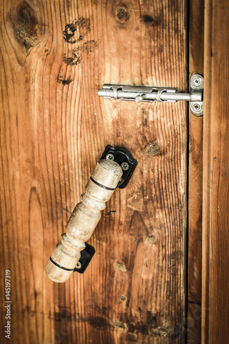 The latch and handle of an old wooden door close-up.
